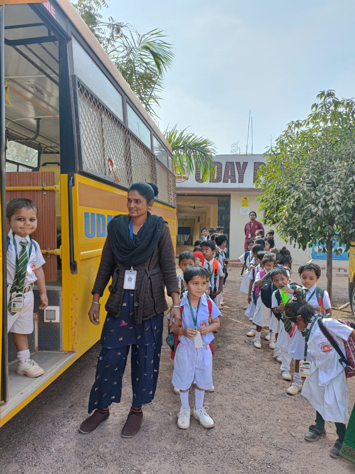 Children boarding the Uday Public School bus with a teacher