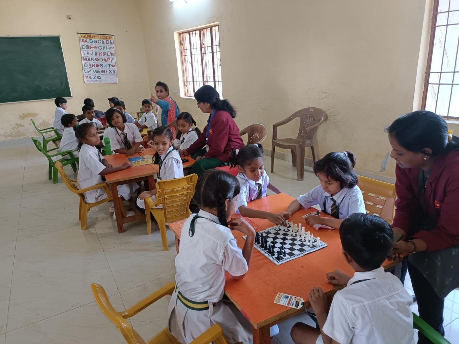 Students playing chess with a teacher